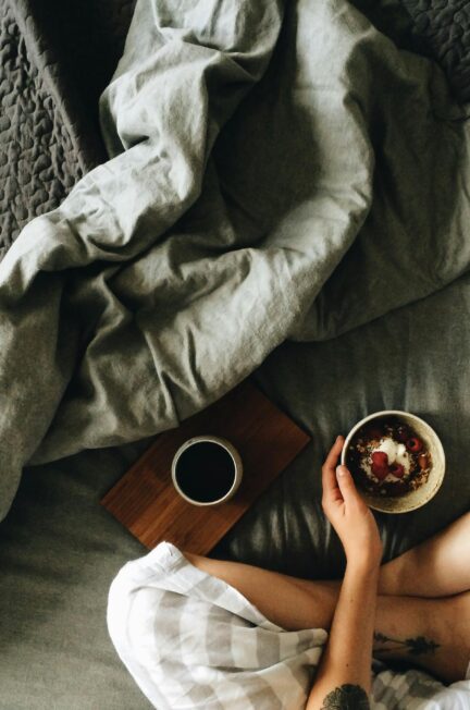 A peaceful morning scene featuring a woman enjoying breakfast and coffee in bed.