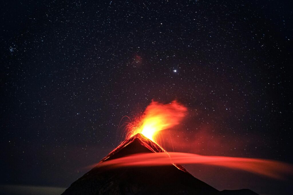 A dramatic volcano eruption in Guatemala beneath a star-filled night sky, showcasing nature's power.
