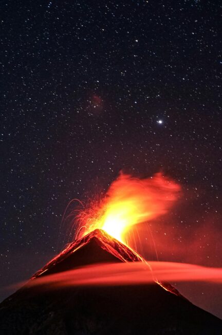 A dramatic volcano eruption in Guatemala beneath a star-filled night sky, showcasing nature's power.